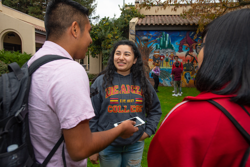 students talking in front of mural