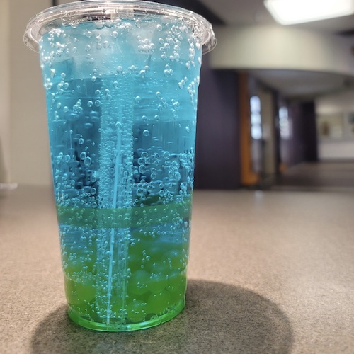 clear cup with blue bubbly drink