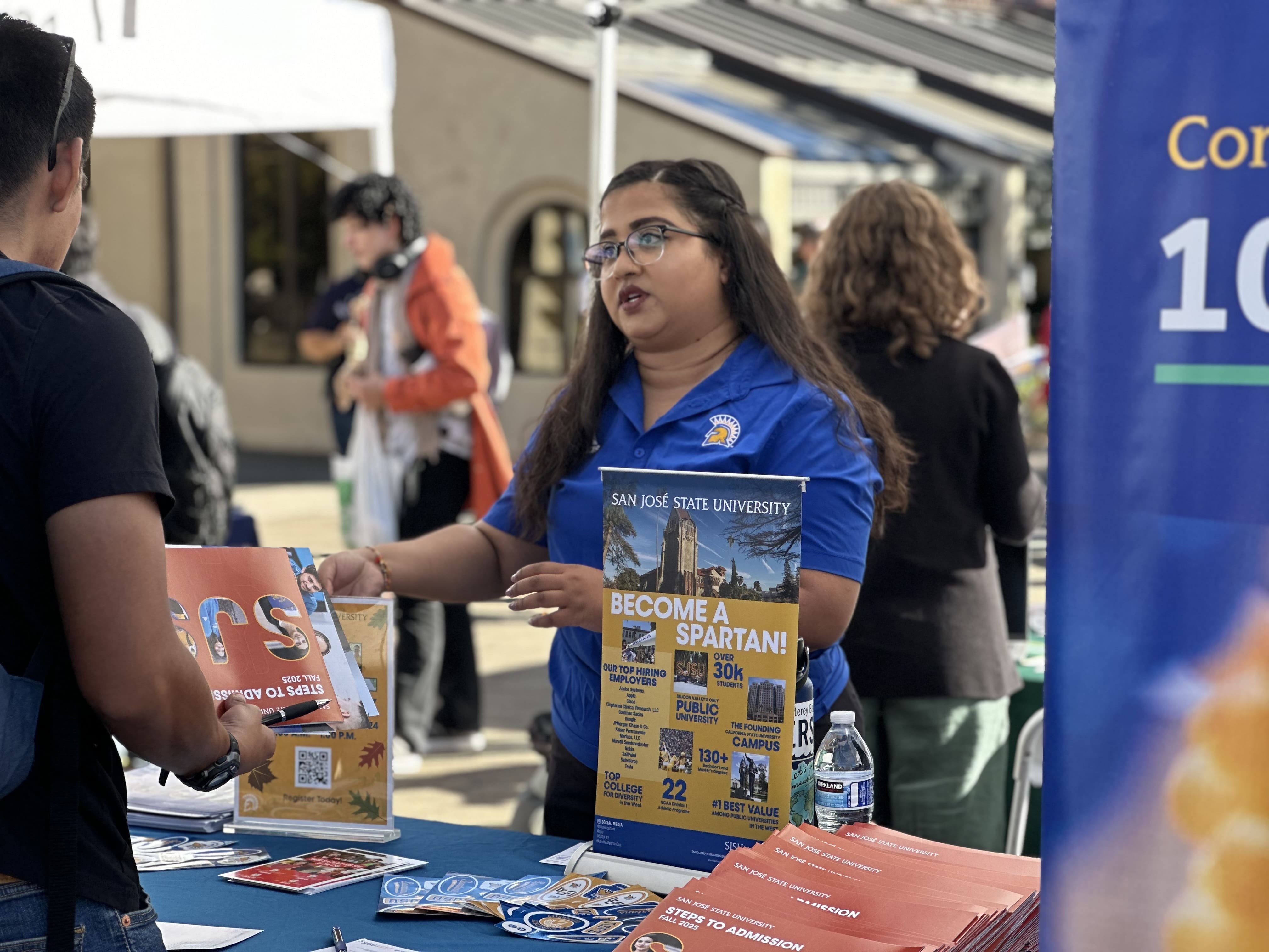 sjsu rep in blue shirt shows brochure to student